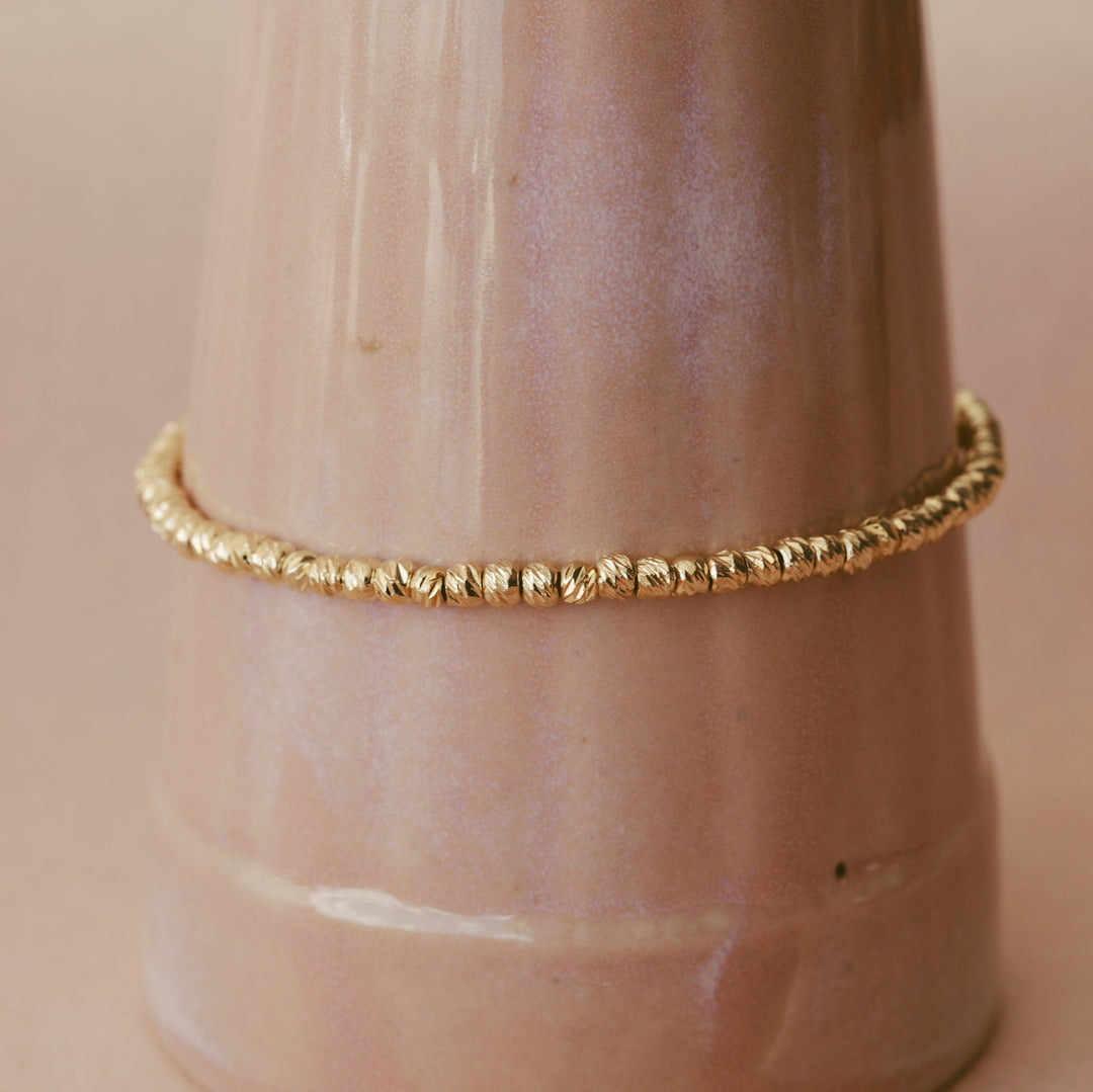 Goldenes Edelstahl-Bracelet mit gebürsteten Perlen an eleganter Vase