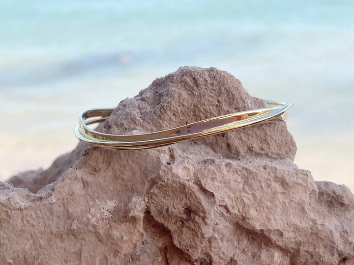 Goldene Armspange auf Felsen vor blauem Meer