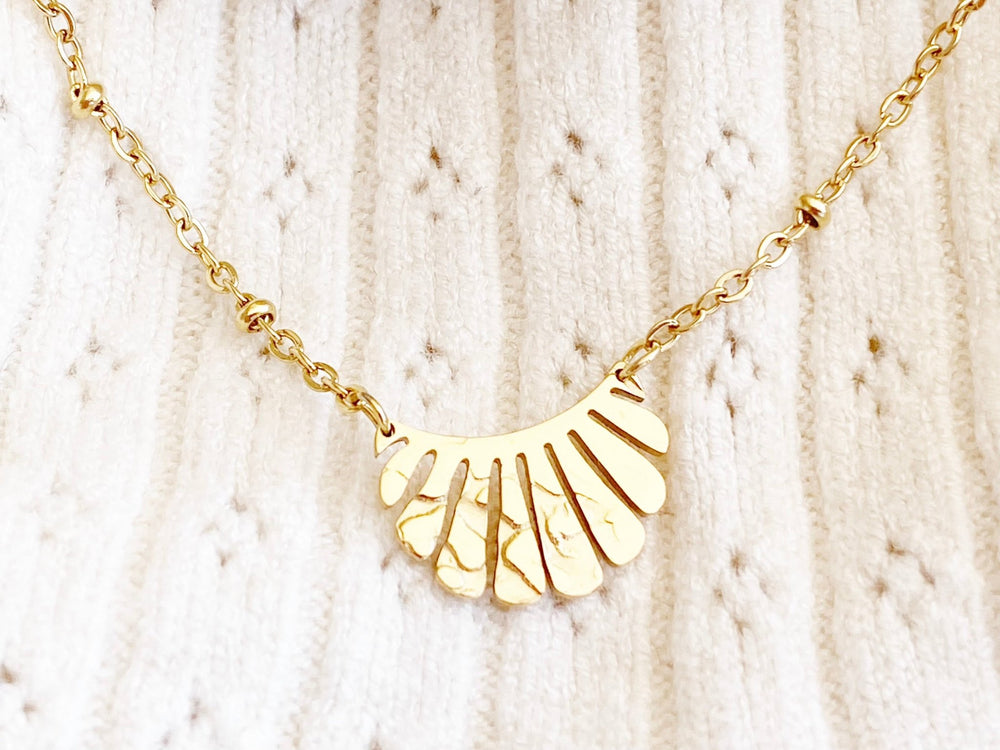 Gold bracelet with pendant against white fabric