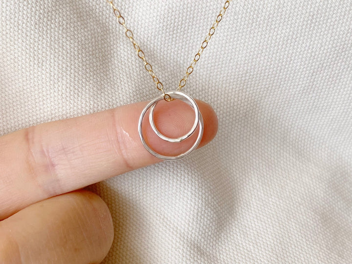 Bicolor: Zarte goldene Halskette mit silbernem Anhänger aus zwei verschlungenen Ringen von Alicia's Diary