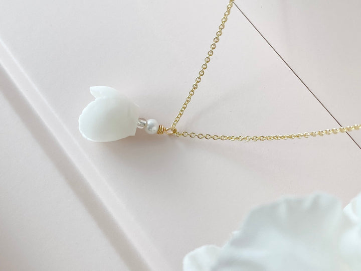 Détail du collier de mariée doré avec pendentif fleur blanche et petite perle d&