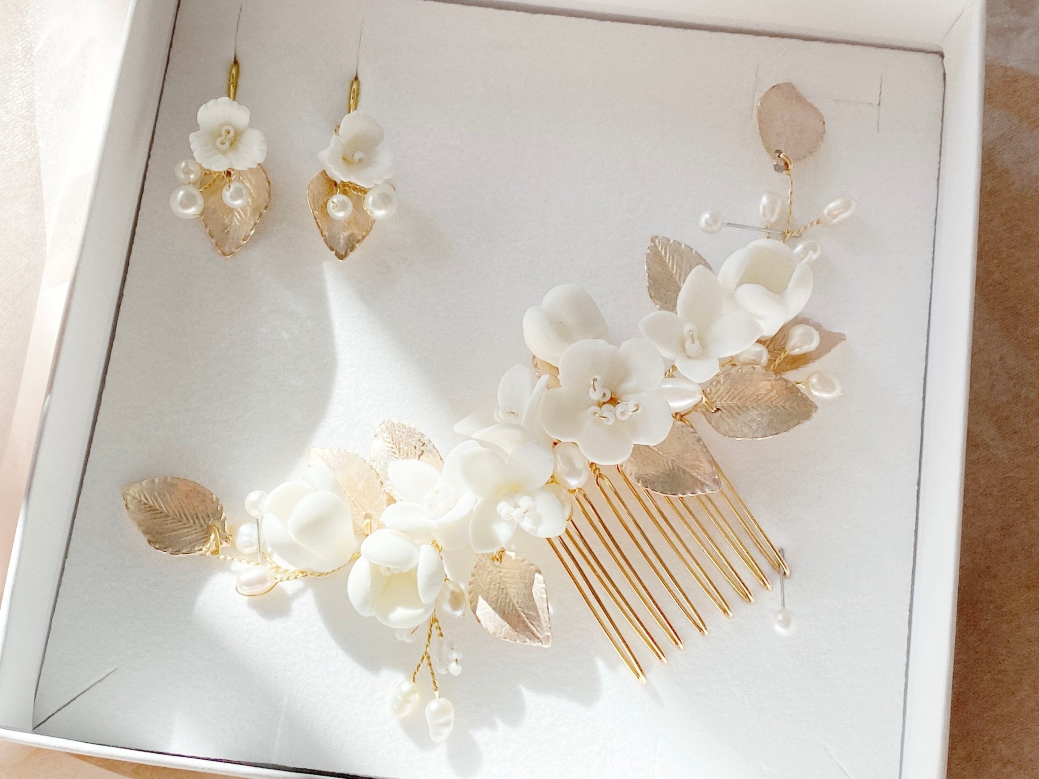 Bridal jewelry set consisting of a golden bridal hair comb with white flowers and earrings from Alicia's Diary
