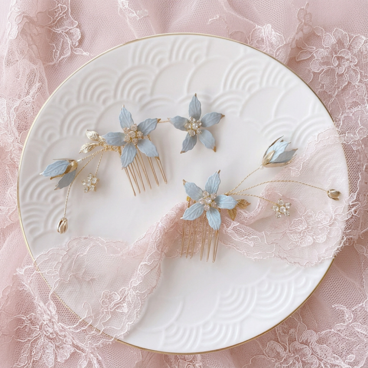 Deux peignes à cheveux dorés ornés de fleurs bleu pastel et de cristaux sur une assiette blanche à dentelle rose