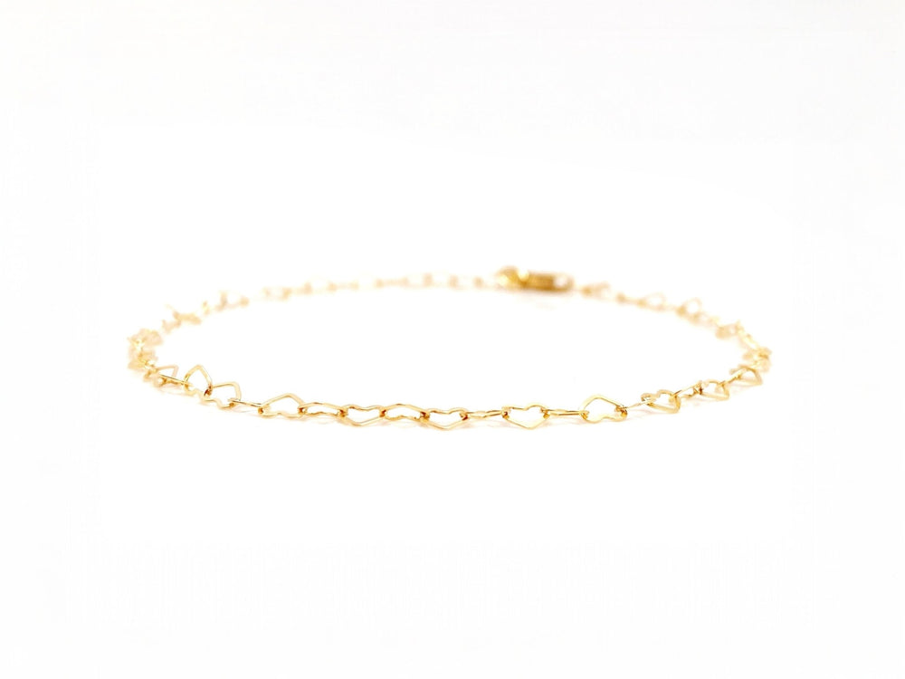 Goldenes Herz Armband vor weißem Hintergrund