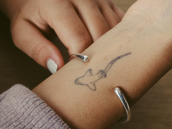 Versilberter Armreif mit unregelmäßiger organischer Struktur, Kaffeeflecken am Handgelenk, Hai Tattoo, grauer Nagellack, Silber Armcuff