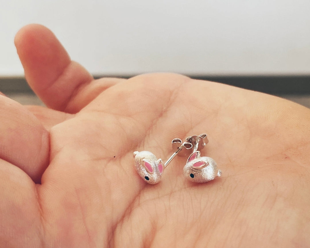 Süße Hasen Ohrstecker für Kinder, kleine Mädchen, Kinderohrstecker aus echtem 925 Silber mit geschliffener Struktur und verspieltem Kaninchen Design, Paar Ohrringe liegend auf Kinderhand - ALICIA'S DIARY