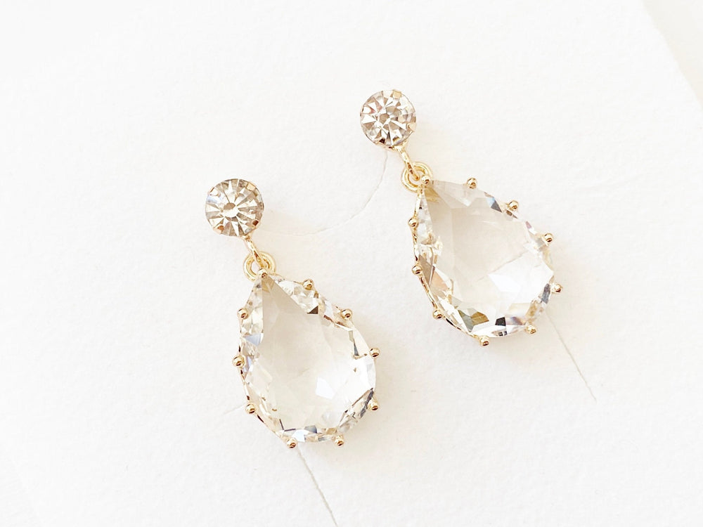Pendientes de novia de clip Gloria dorados con brillantes gotas de cristal, fotografiados en diagonal