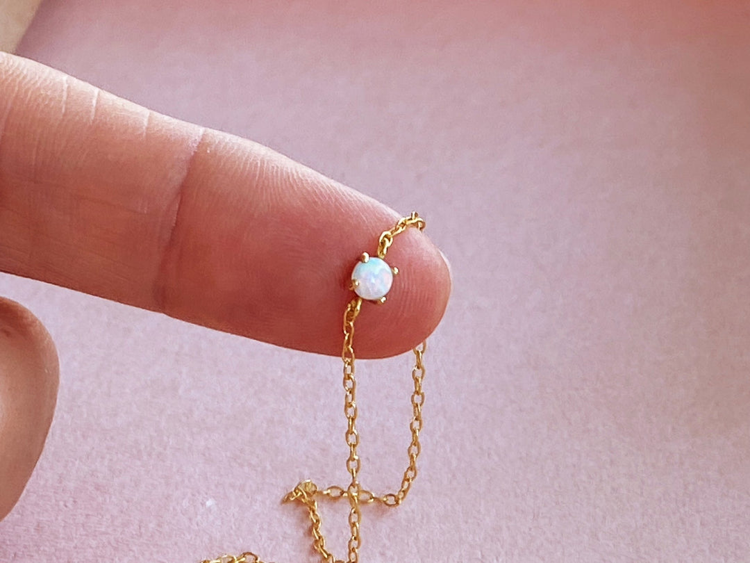 Zartes Gold Armband mit kleinem Opalstein mit rundem Schliff, winzige Detailaufnahme auf der Fingerspitze - ALICIA'S DIARY