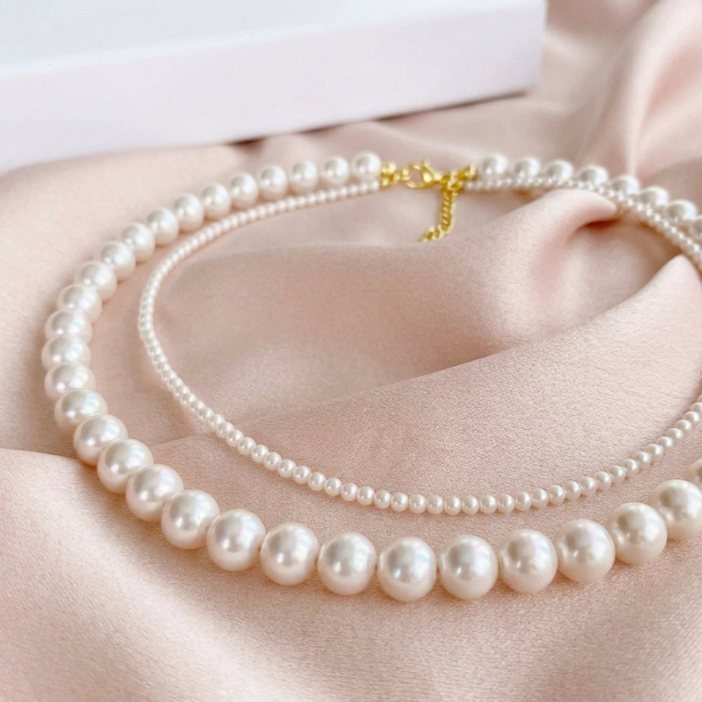 Collier de perles multirangs Sophie drapé avec élégance sur une soie fluide couleur champagne