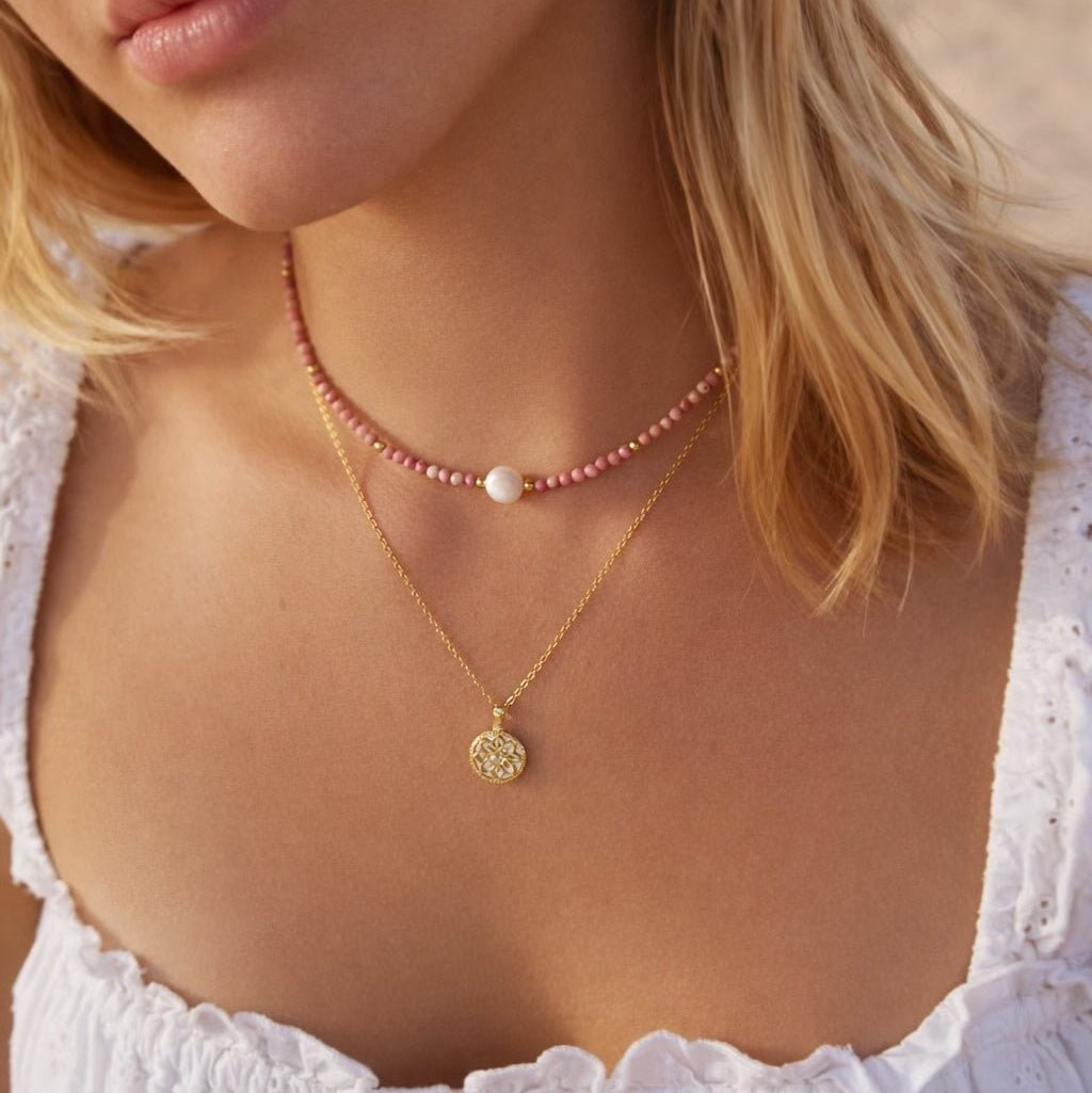 Pink natural jewelry necklace with pink and rose-colored beads, gold-plated 925 silver chain in a necklace stack, beach jewelry, white summer dress
