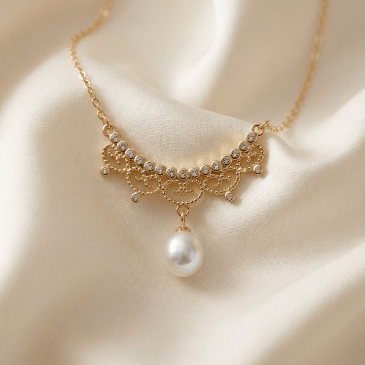 Gros plan sur le pendentif filigrane du collier perle romantique posé sur du satin