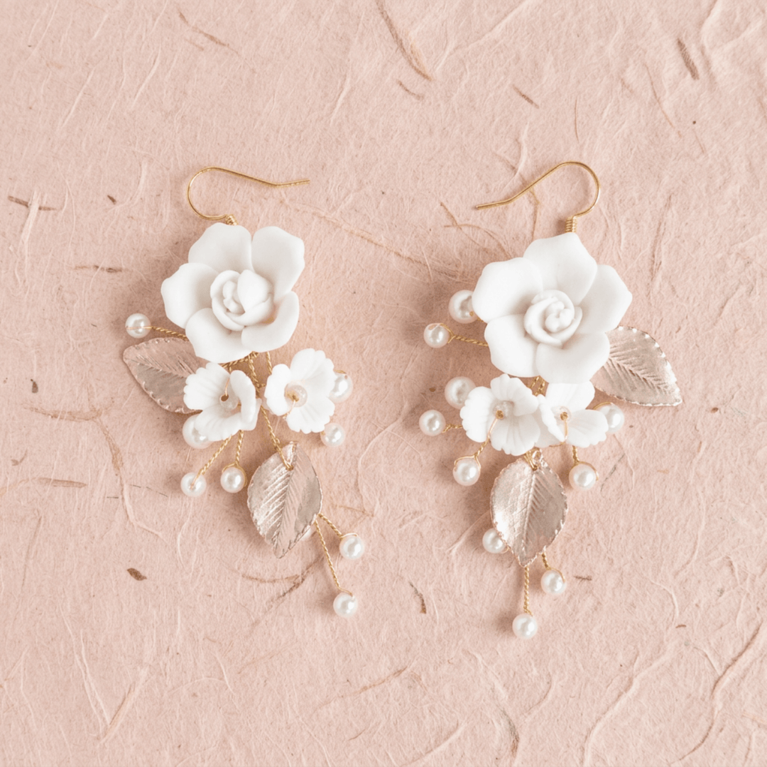 Weiße Blumenohrringe Rosalie mit Perlen und Blättern auf beigem Naturpapier