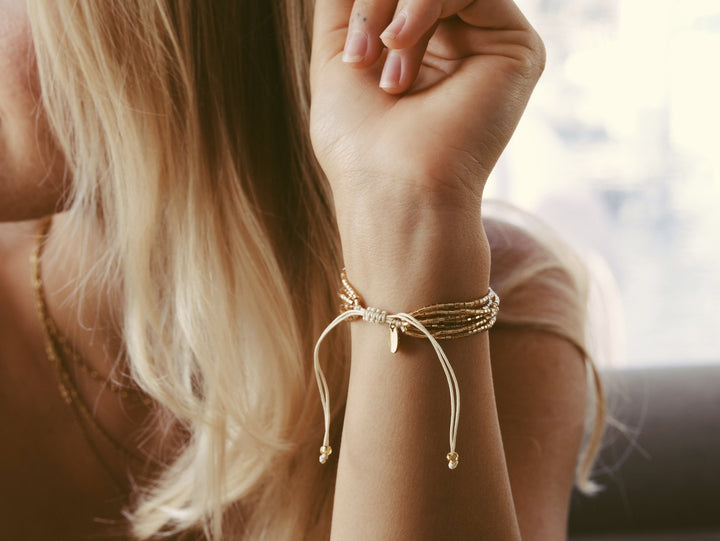 Blonde junge Frau mit Perlenarmband mit Schiebeknoten und Edelstahl Plättchen, schöner Schmuck von Alicia&