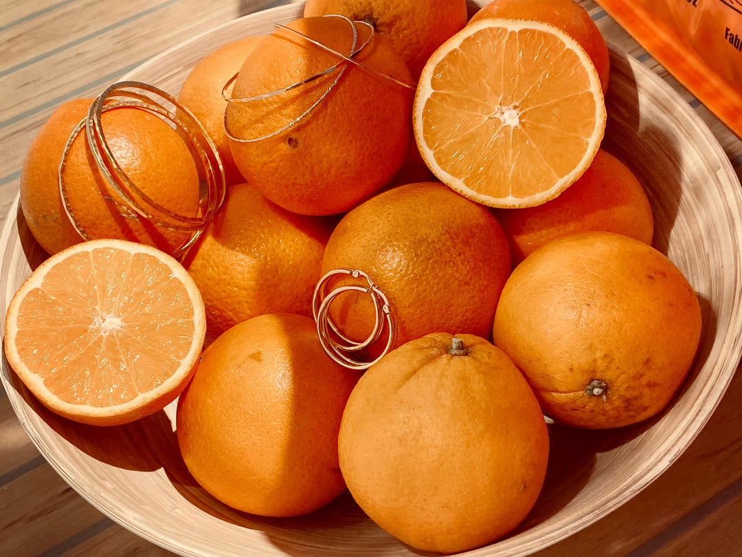 Goldene Armreifen im gehauenen Stil und Creolen als Dekoration in Orangen