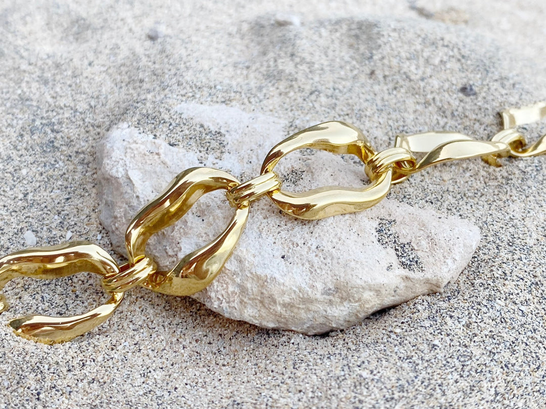 Goldenes Armband im Chunky Style auf Strandsand und weißem Stein für Beach Girl Outfits, schöner Schmuck von Alicia's Diary