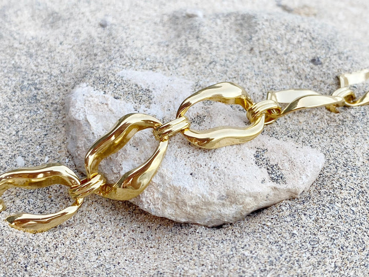 Goldenes Armband im Chunky Style auf Strandsand und weißem Stein für Beach Girl Outfits, schöner Schmuck von Alicia's Diary