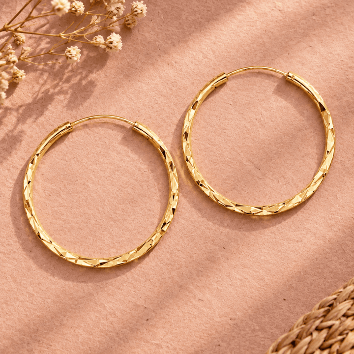 Champagnergoldene Creolen mit Diamond Cut Finish liegend neben zarten Trockenblumen